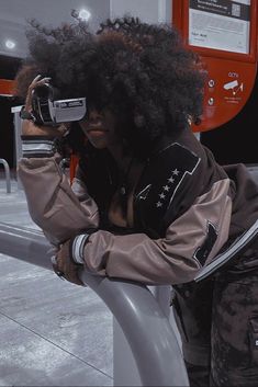 a woman with an afro is holding a camera