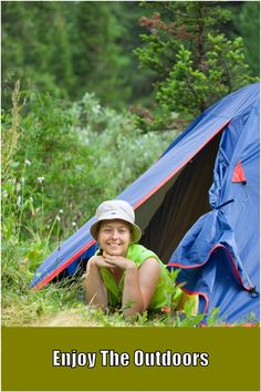 a woman sitting in front of a blue tent with the words enjoy the outdoorss