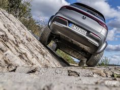 the rear end of a silver car on a rocky road