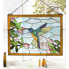 a stained glass window with a hummingbird on it's side hanging from a chain