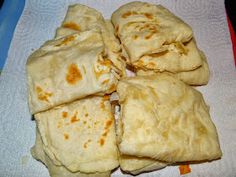 four pita breads stacked on top of each other in a white dish towel