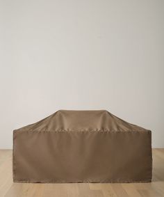 an outdoor bbq cover sitting on top of a hard wood floor in front of a white wall