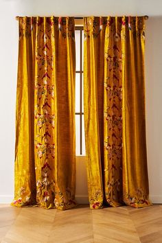 an open window with yellow curtains and wooden flooring in front of the windowsill