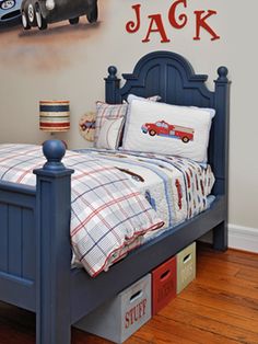 a bedroom with a blue bed and red cars on the wall above it is also a toy car