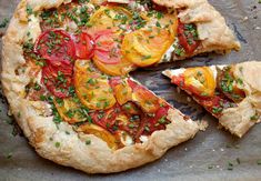 a pizza with tomatoes, cheese and herbs cut into slices on a baking sheet ready to be eaten