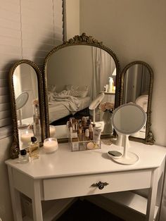 a white vanity with three mirrors on it and some candles in front of the mirror