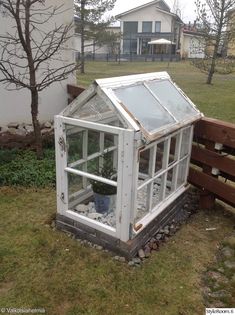 a small white greenhouse sitting on top of a lush green field