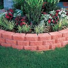 a brick flower bed in the middle of some grass