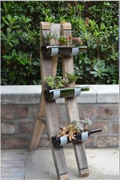 a wooden wine rack with bottles and plants in it