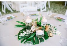 an arrangement of flowers and candles on a white table cloth at a wedding or reception