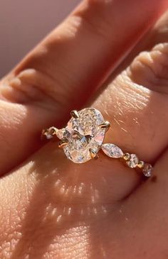 a woman's hand with a diamond ring on top of her finger and an engagement band