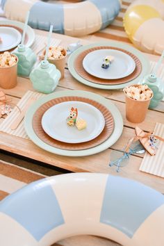 the table is set with plates, cups, and desserts on top of it