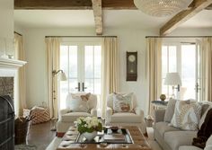 a living room filled with furniture and a fire place in front of a window covered in curtains