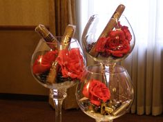 two wine goblets with red roses in them