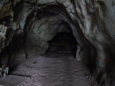 there is a small cave with some people walking in the tunnel and one person sitting on the floor