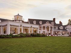 a large white house sitting on top of a lush green field