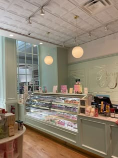 the inside of a bakery with lots of food on display and lights hanging from the ceiling