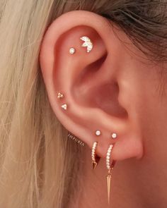 a woman's ear with three different piercings