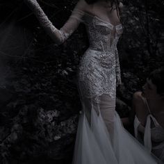 a woman in a white dress standing next to a tree