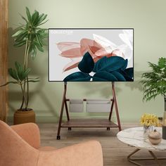 a flat screen tv sitting on top of a wooden stand in a living room next to potted plants