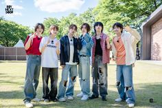 five young men standing in the grass with one holding his hand up to his face