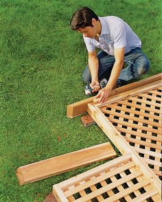 a man is working on some wood pieces in the grass with a drill and screwdriver