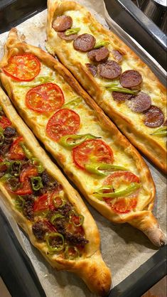 two long pizzas sitting on top of a pan