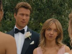 a man in a tuxedo standing next to two women