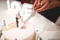 two people cutting into a wedding cake with a knife and fork on top of it