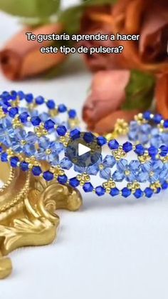 a gold and blue beaded bracelet sitting on top of a table next to flowers