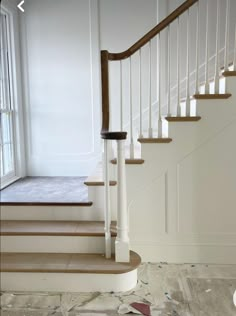 an empty room with white walls and carpeted stairs in front of a window that has torn paper on the floor