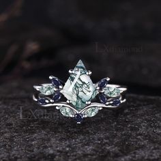 a ring with blue and white stones on it sitting on top of a black rock