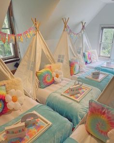 four beds with colorful pillows and teepees on them