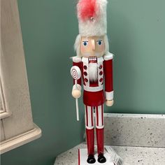 a red and white nutcracker is standing in front of a green painted wall