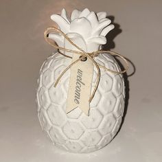 a white ceramic pineapple shaped vase with a ribbon tied around the top and bottom