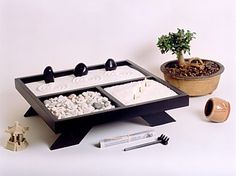 a bonsai tree sits on top of a black tray with white rocks in it