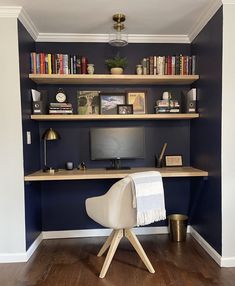 a desk with a computer and books on it in front of a book shelf filled with books