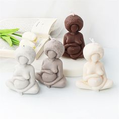 three small buddha figurines sitting next to each other in front of an open book