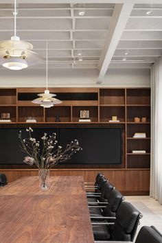 an empty conference room with wooden tables and black leather chairs in front of a chalkboard