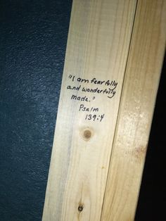 a piece of wood that has writing on it and is next to a black wall