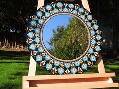 a mirror sitting on top of a wooden easel in the middle of a field