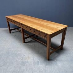 an old wooden desk with drawers on the bottom and one drawer at the top, against a blue wall