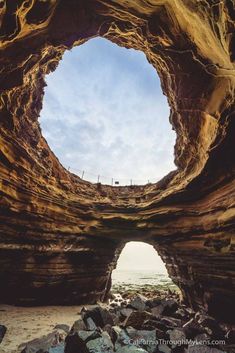 a hole in the ground with rocks and water around it that looks like an ocean cave