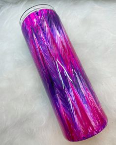 a pink and purple tumbler sitting on top of a white fur covered floor next to a window