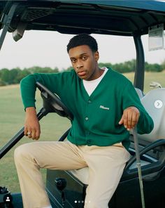 a man sitting in the driver's seat of a golf cart, holding a club