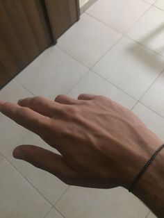 a person's hand with a bracelet on top of it and a door in the background