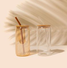 two tumblers with straws in them sitting next to each other