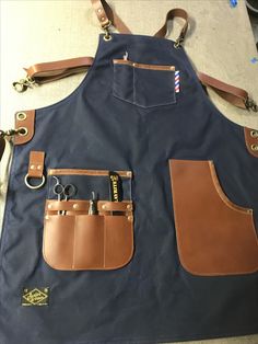 a blue apron with brown leather straps and pocket pockets on the front, two pairs of scissors in each pocket