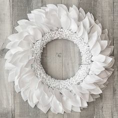 a white wreath is hanging on a wooden wall