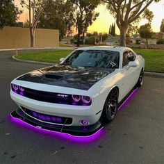 a white and black car with purple lights on it's hood is parked in the street